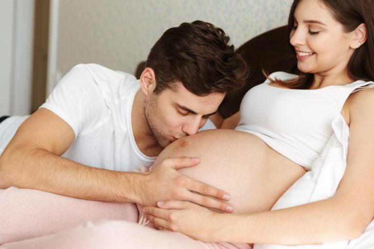 Homem beijando a barriga de sua esposa grávida