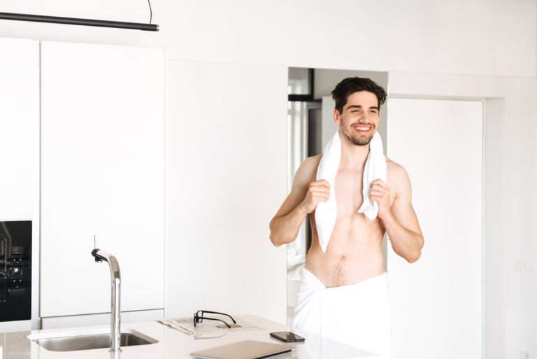 Homem saindo do banho com toalha arramada na cintura