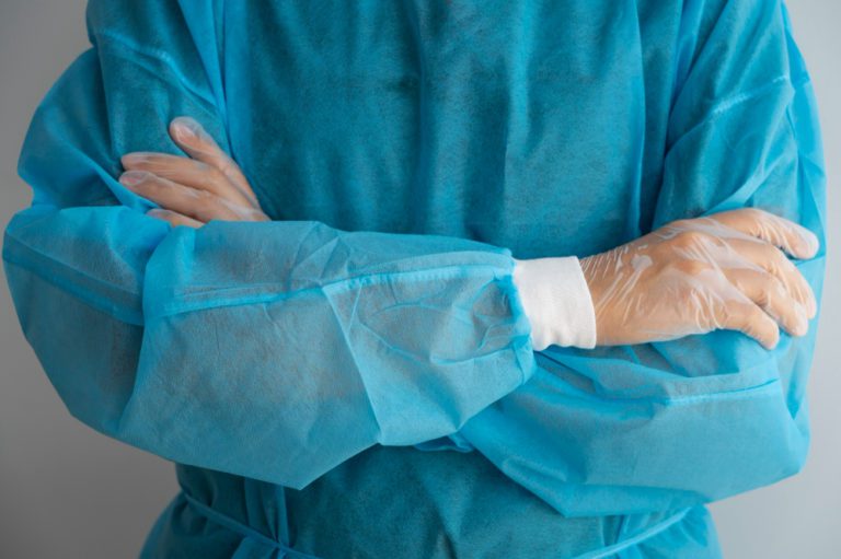 Cirurgião de braços cruzados, vestindo o avental cirúrgico para a cirurgia de doença de peyronie