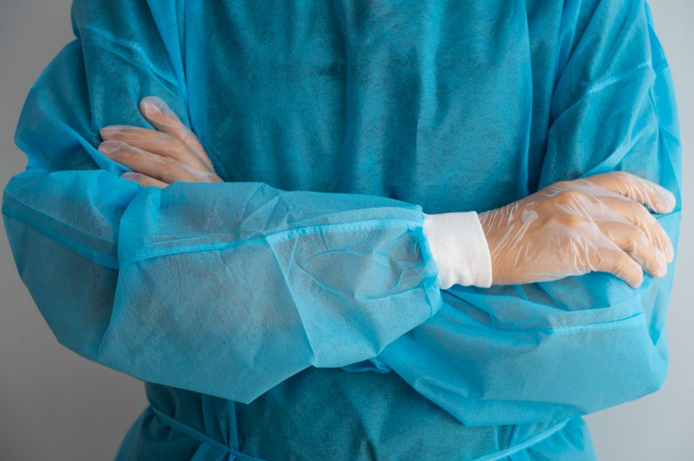 Cirurgião de braços cruzados, vestindo o avental cirúrgico para a cirurgia de doença de peyronie