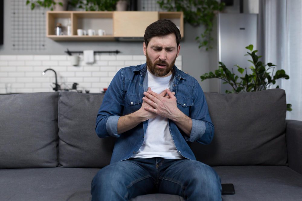 Homem no sofá com dor no peito se perguntando se o cardiopata pode tomar viagra