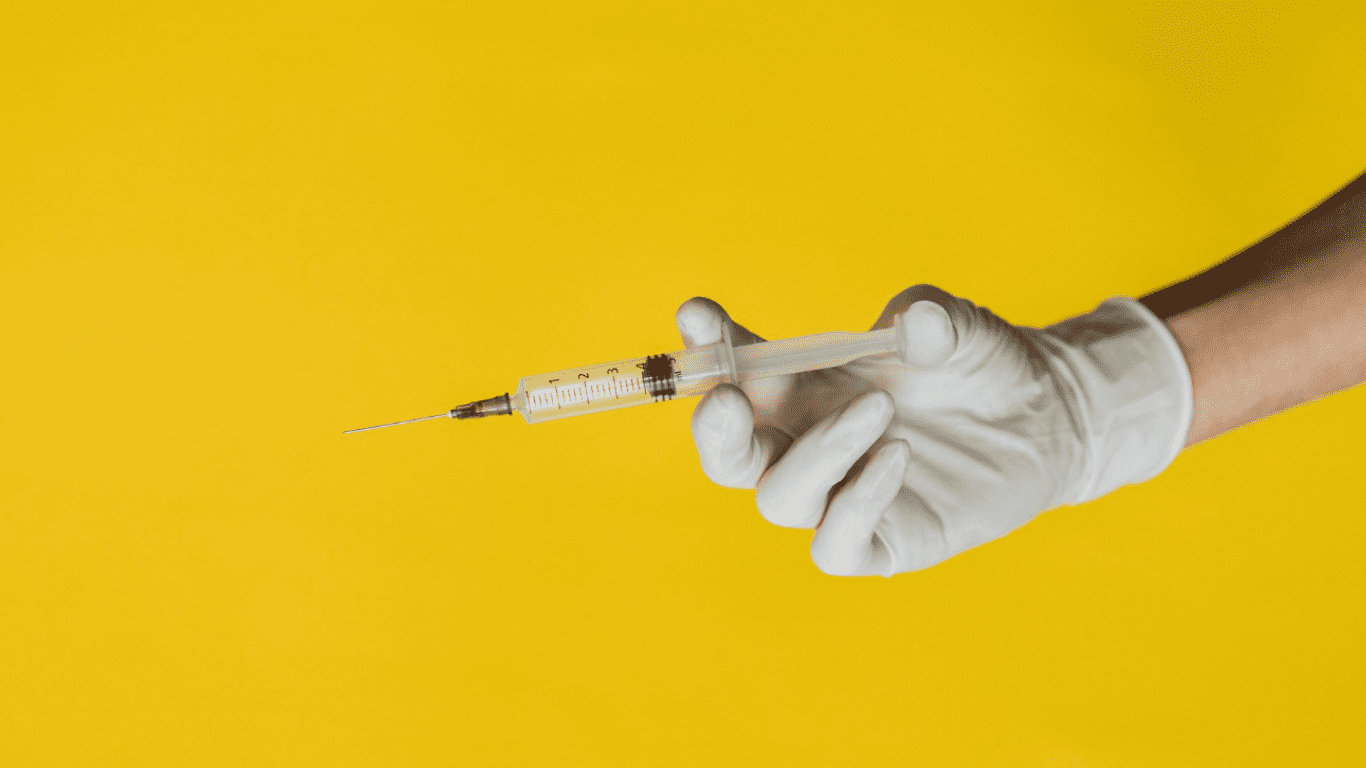 Mão do médico com luva, segurando uma seringa para aplicação de Urofill, mitos e verdades