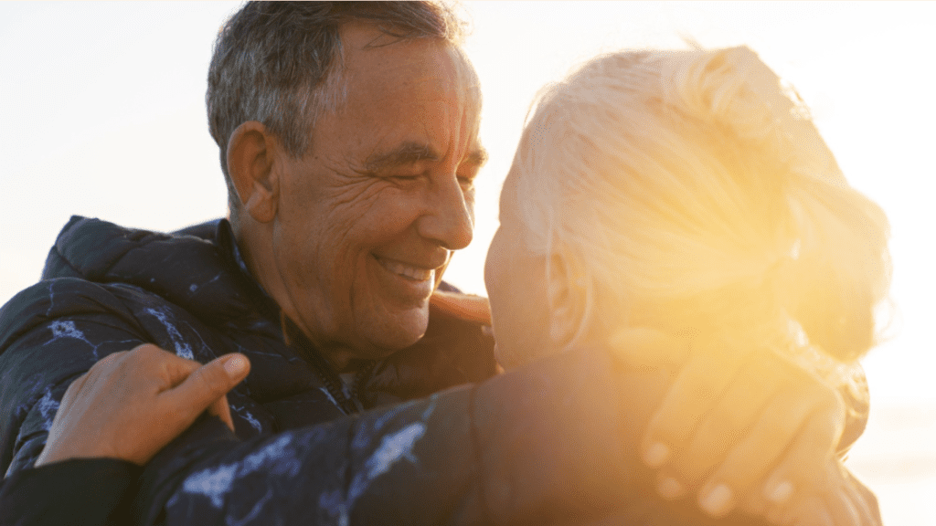 Homem abraçando sua mulher sob a luz do sol, falando sobre como melhorar sua vida sexual com a prótese peniana
