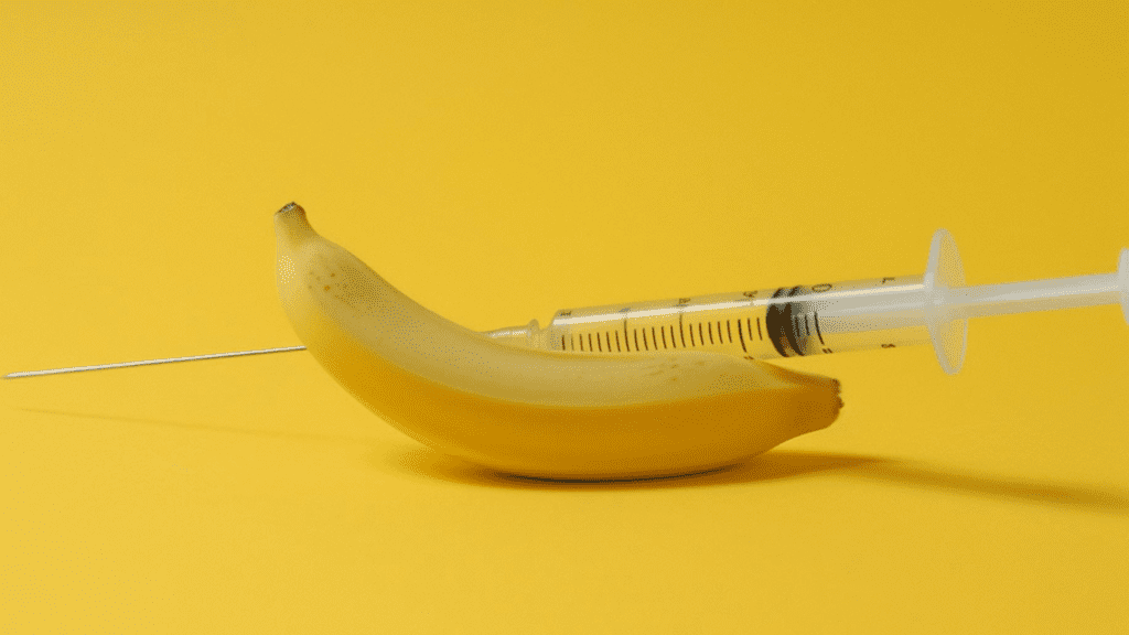 Seringa sendo aplicada em banana sobre fundo amarelo, para ilustrar os resultados do Urofill