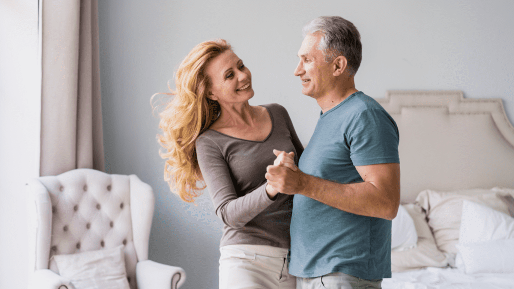 Homem dançando com sua mulher dentro de casa, falando sobre como melhorar seu relacionamento com a prótese peniana