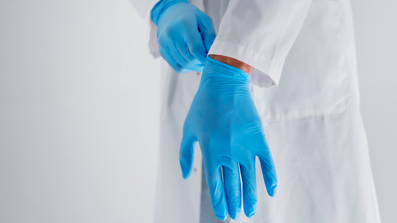 Médico calçando luvas para fazer o exame de toque no novembro azul