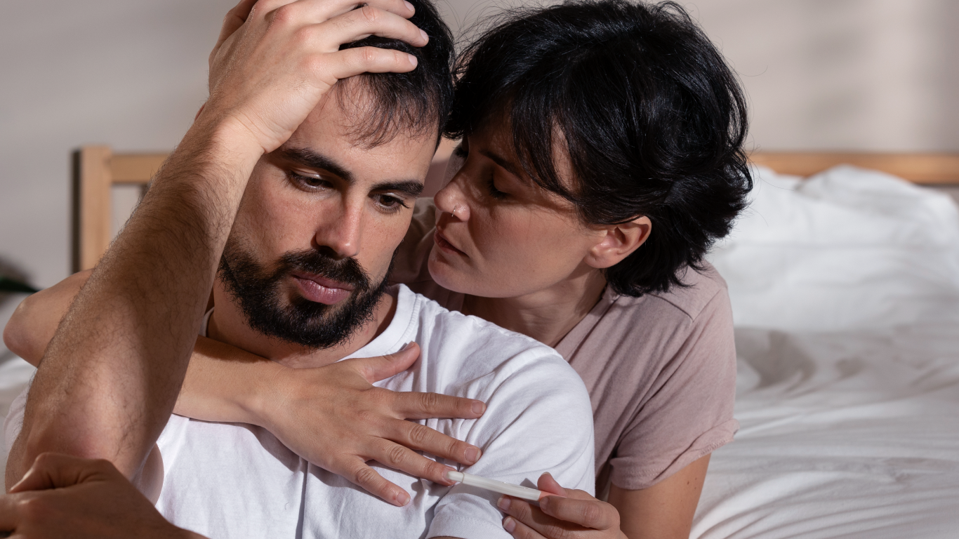 Casal consolando-se mutuamente, pensando em quando buscar ajuda médica para infertilidade masculina