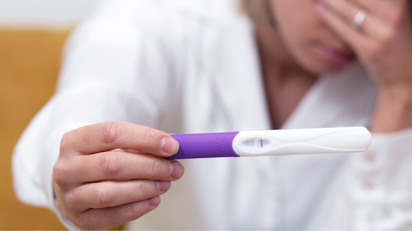 Mulher com um exame de gravidez, pensando na relação entre a fertilidade masculina e a idade